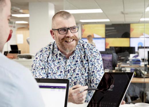 a bearded man smiles in an office environment